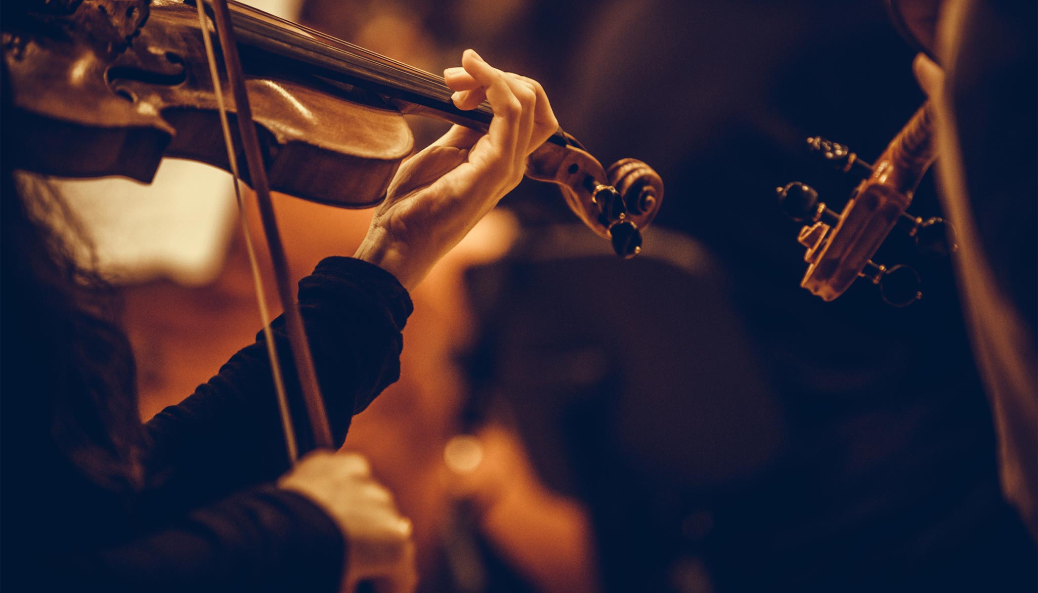 Close up of hands playing violin in orchestra